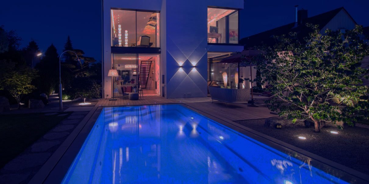 Beleuchteter Compass-Pool am Abend vor einem Haus