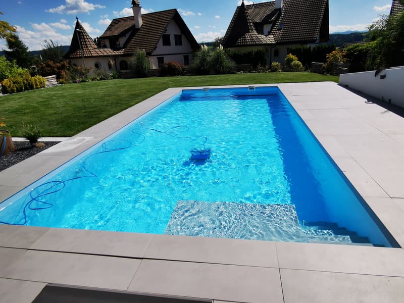 Rechteckiger Pool mit Treppe, hellen Randsteinen und Sommerhimmel – ein Badipool-Projekt